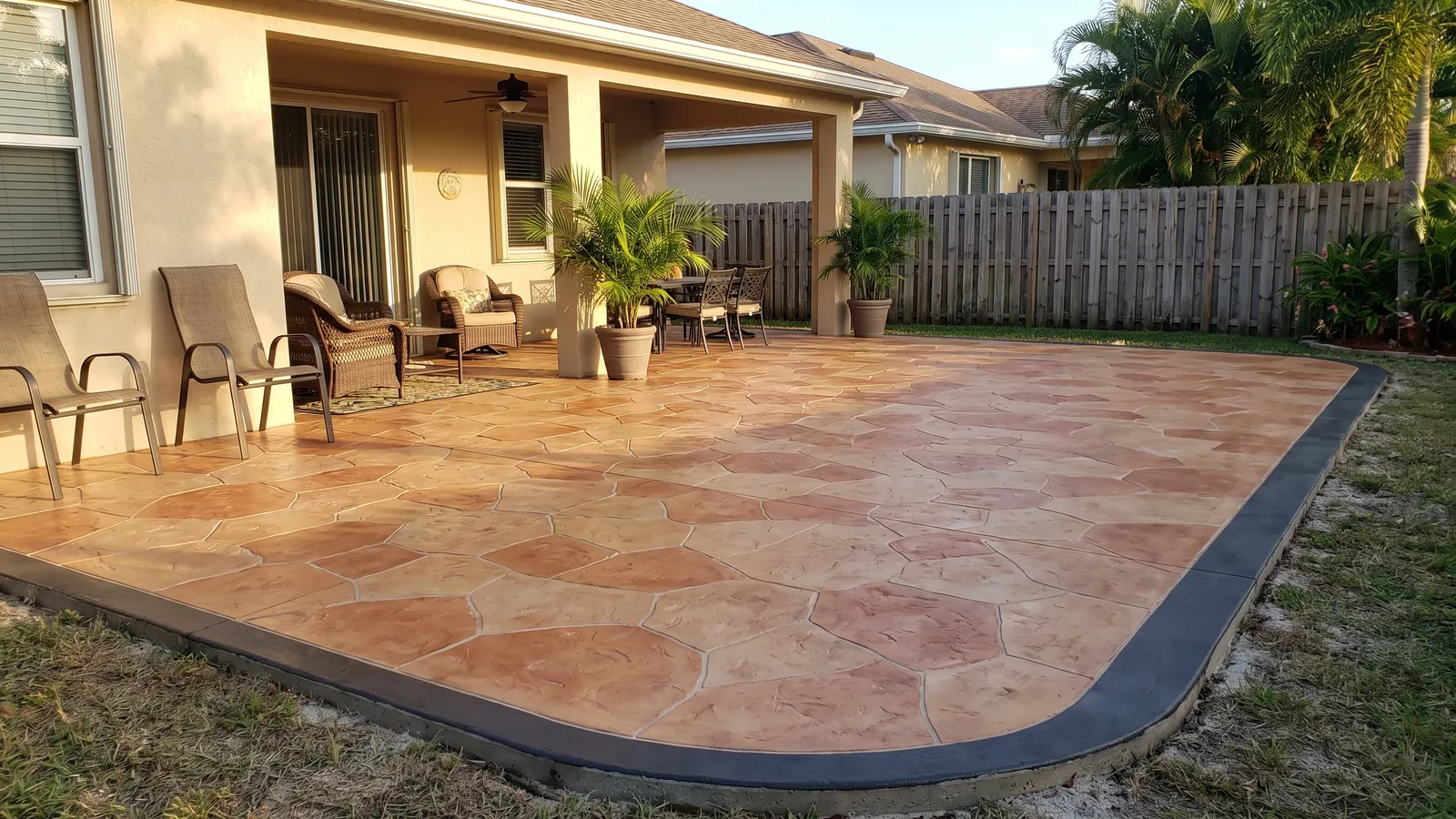 Stamped concrete patio in a random flagstone pattern with a warm integral color and a smooth border behind a Florida home